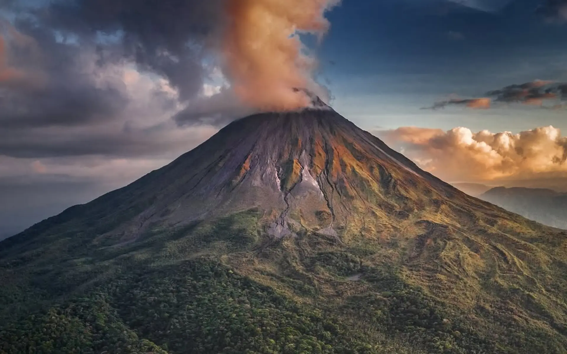 Volcán Arenal al atardecer, con una nube iluminada por la luz cálida sobre la cumbre